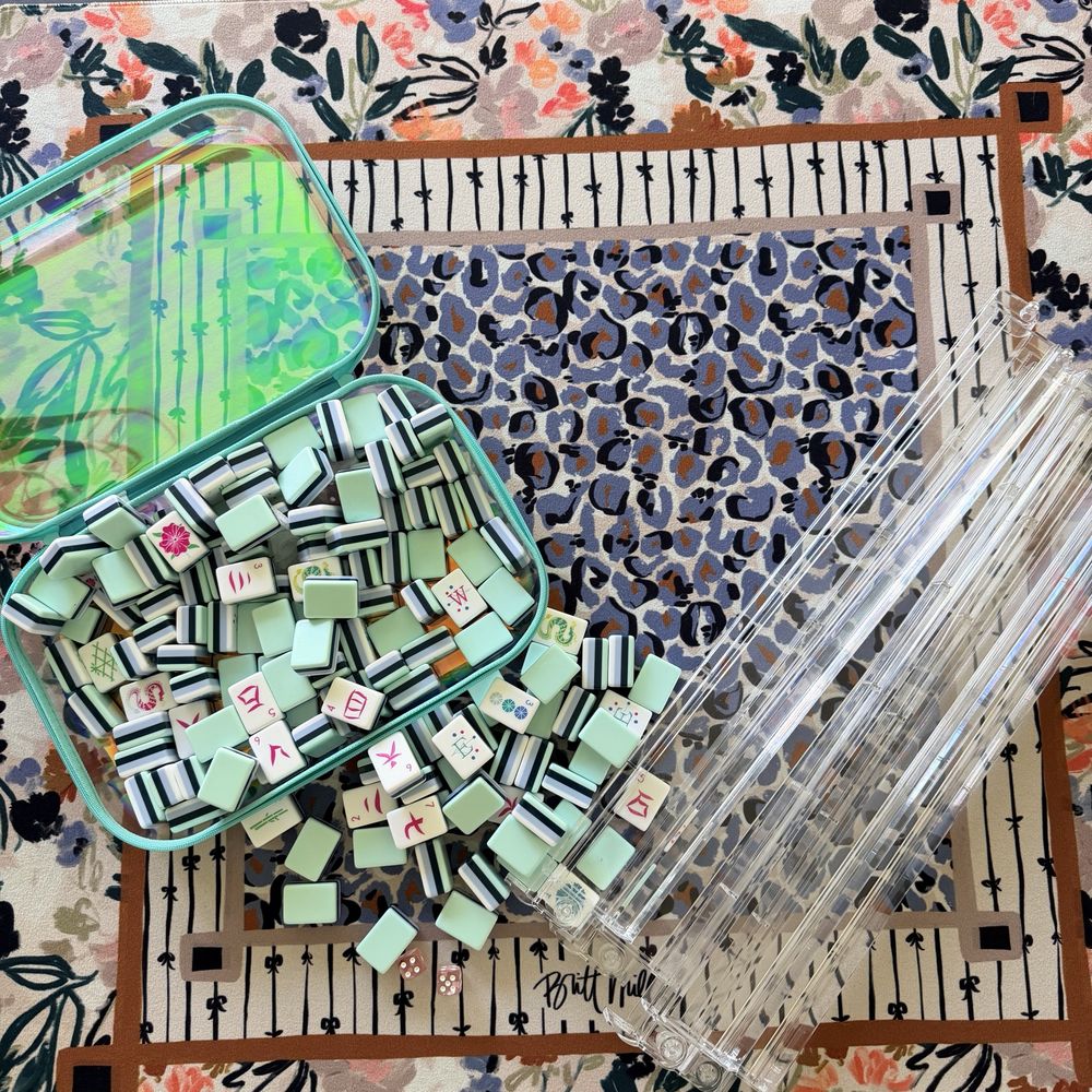 Mint and navy striped mahjong tiles with racks and dice on a floral and leopard-print mat
