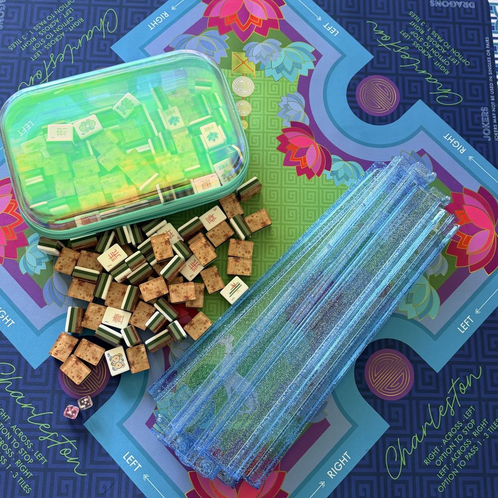 Woodgrain speckled mahjong tiles with clear racks on a blue lotus-print mat